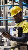 Vertical Smart factory repairman using tablet to analyze IoT sensors data before upgrading assembly lines. Industry 4.0 plant staff member performing system diagnostics to reduce errors, camera A video