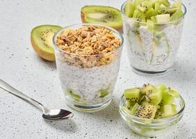 Glass filled with chia seed pudding, layered with diced kiwi at the bottom and topped with crunchy granola. Top photo