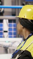 Vertical Technician walking in smart factory, inspecting systems, ensuring machinery operates at optimal efficiency. Industry 4.0 plant mechanic overseeing equipment, maintaining continuous operations, camera B video