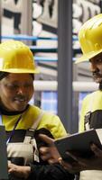 Vertical Solar panels factory engineering team analyzes performance data on laptop to predict gear failures. Teamworking photovoltaics plant colleagues following maintenance procedures, camera B video