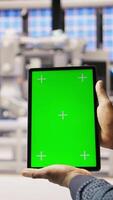Vertical Smart factory expert uses green screen tablet to implement automated workflows. Industry 4.0 plant technician integrates sensors into production using chroma key device, camera A close up video