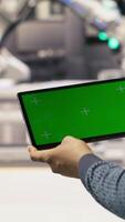 Vertical Photovoltaics plant worker uses chroma key notebook to follow maintenance procedures. Solar panels factory engineer analyzes performance data with isolated screen laptop, camera B close up video