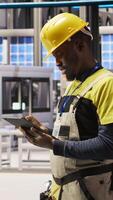 Vertical Engineer oversees solar panel production lines equipment using tablet app. Worker maintains photovoltaic assembly systems in automated industry 4.0 factory using digital device application, camera A video