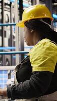 Vertical Smart solar panels factory worker typing on PC keyboard, testing automated systems, doing maintenance. Woman in industry 4.0 photovoltaics plant using computer to inspect gear and fix bugs, camera A video
