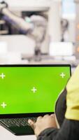 Vertical Engineer in photovoltaics factory using chroma key laptop to look at system performance metrics. Worker in industry 4.0 plant using green screen mockup notebook to track energy production, camera B video