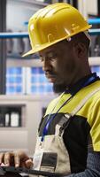 Vertical Industry 4.0 plant engineer following maintenance procedures to mend bugs. Smart factory professional analyzing data on laptop to predict production lines and robotic arms failures, camera A video