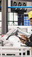 Vertical Technician overseeing solar energy installation process, troubleshooting automated machinery, calibrating robotic arms in renewable energy manufacturing facility, camera A video