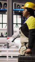 Vertical Smart factory mechanic installing automated workflows control systems, computerizing operations. Repairman walking in industry 4.0 plant with toolbox, integrating sensors into production, camera A video