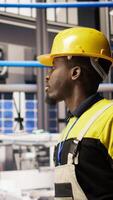 Vertical Man holding toolbox walking in factory, inspecting systems, ensuring machinery operates at optimal efficiency. Industry 4.0 plant repairman overseeing infrastructure, maintaining operations, camera A video