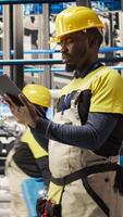 Vertical Industrial plant technician using tablet to implement green energy solutions, integrating solar tech in assembly systems. Smart factory worker enhancing production efficiency using device, camera A video