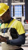 Vertical Technician in solar panels factory does maintenance using tablet, analyzing IoT sensor data. Industry 4.0 plant expert managing operational reliability of photovoltaic systems using device, camera A video