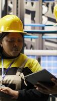 Vertical Team of smart factory mechanics working together to test systems, doing maintenance. Industry 4.0 plant teamworking repairmen inspecting equipment to identify glitches, doing brainstorming, camera B video