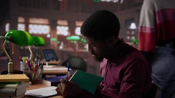 African american guy studies for a critical law exam and reading specialty books to complete class notes with reliable academic information. Studying in the library before the test. Camera B. video