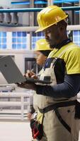 Vertical Smart factory specialist, testing automated systems, monitoring production performance. Industry 4.0 plant technician inspecting machinery to identify and optimize bottlenecks, camera A video