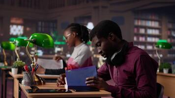 Noisy black guy disturbing pupils at the library by speaking very loud, being rude and answering phone call in the study area. Disruptive annoying man asked to keep silence. Camera A. video