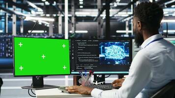 Data center admin using green screen PC to do node tree programming, optimizing resource allocation. Man in server room uses mockup computer predictive AI visualization systems, camera B video