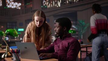 Multiethnic pupils working on team project assignment at campus library, consulting academic database and research collection with various books. Young adults guarantee high grades. Camera B. video