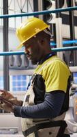Vertical Smart factory mechanic testing automated systems, doing preventive maintenance. Industry 4.0 plant repairman inspecting equipment to identify and service glitches, camera A video