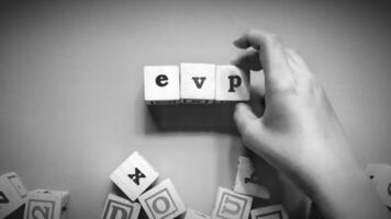 Man holding wooden cube with EVP written on it, Employee Value Proposition concept isolated on a dark background. photo