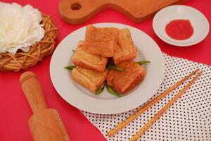 a plate of fried tofu, neatly arranged and garnished with green chili peppers photo