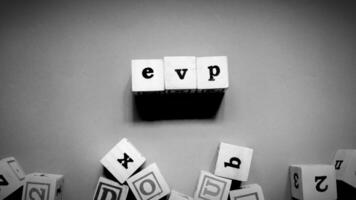 Top view of wooden cube labeled EVP, Employee Value Proposition concept isolated on a dark background. photo