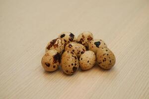 a cluster of quail eggs placed on a light wooden surface photo