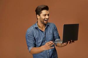 Handsome man looks shocked while using his laptop. photo