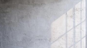 Textured gray wall with window shadow light falling diagonally across rough surface creating a soft and moody architectural background. photo