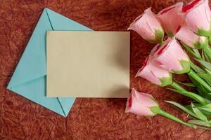 Romantic roses with envelope and card on textured background. photo