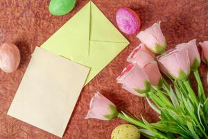 Colorful arrangement with pastel roses, Easter eggs and stationery. photo
