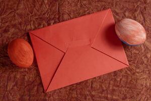 Red envelope with decorative painted eggs on a rustic background. photo