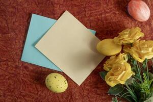 Easter decorations with yellow roses, painted eggs and colored paper. photo