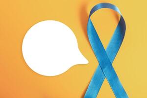 Blue awareness ribbon with blank speech bubble on yellow background photo