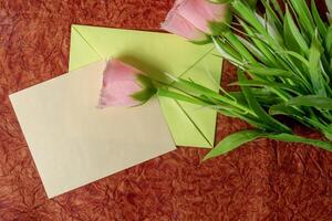 Pink roses in an envelope with a blank greeting card. photo