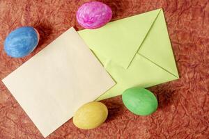 Colorful Easter eggs, envelope and blank card on textured background. photo