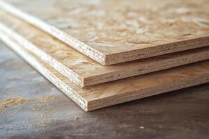 Layers of oriented strand board stacked on a wooden surface in workshop photo