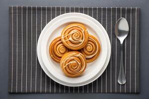 Stack of Glazed Cinnamon Rolls on Modern Table Mat photo