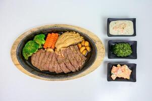 Japanese wagyu beef slices set with vegetables and sauce on wooden tray at table photo