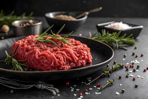 Raw beef on a black plate with spices and herbs photo