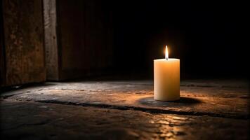 Candle casting light in a dark room on a wooden floor photo