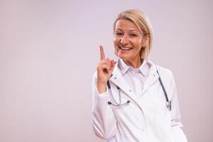 A mature healthcare worker pointing toward a solution in her medical practice. Her professionalism is evident in her thoughtful pose and confident expression. photo