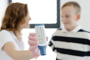 Pediatric pulmonologist helping boy with peak flow meter. Pulmonologist, medical doctor who specializes in the diagnosis and treatment of diseases and disorders of respiratory system. photo