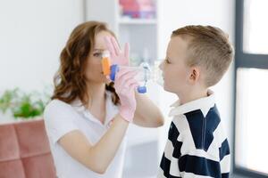 Boy with allergic asthma, inhaling his medication through spacer while sitting in doctors office. photo