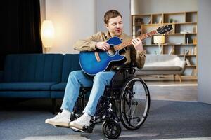 Man with a disability sitting in wheelchair playing on guitar at home photo
