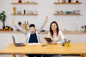 Woman helps a boy with his lessons using a tablet and a globe. A homeschooling student does his homework with the help of a tutor. photo