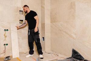 Construction Worker Installing Large Travertine Tiles in Modern Bathroom photo