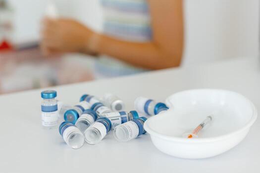 Vials and syringe on white table. Vaccination and immunization for people. photo