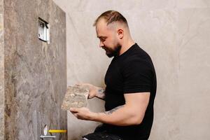 Tiler installing large format tile on bathroom wall photo