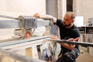 Construction worker cutting tile with tile saw during renovation works photo