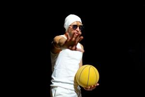 Basketball player in a white outfit poses confidently with a yellow ball in night park photo